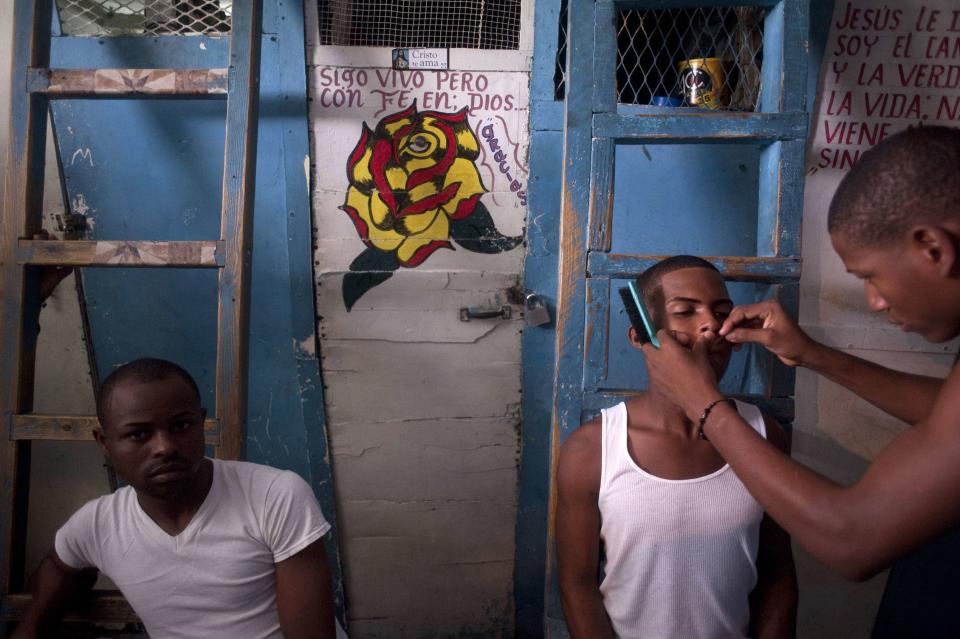 A prisoner shaves a fellow inmate in the old wing of the Najayo prison which is being renovated in San Cristobal, May 13, 2014. Ten years after the country opened its first prison designed with a focus on education and clean living conditions and staffed by graduates from a newly created academy for penitentiary studies, the New Model of Prison Management is gaining recognition from other countries in the region trying to reduce prison populations and cut recidivism rates. Picture taken May 13, 2014. REUTERS/Ricardo Rojas (DOMINICAN REPUBLIC - Tags: CRIME LAW POLITICS)