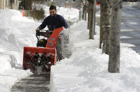 A man uses a snow blower to clear a side walk after a major winter storm swept over Washington January 25, 2016. REUTERS/Joshua Roberts