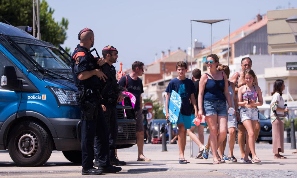 Beachgoers walk past police officers in Cambrils, Spain