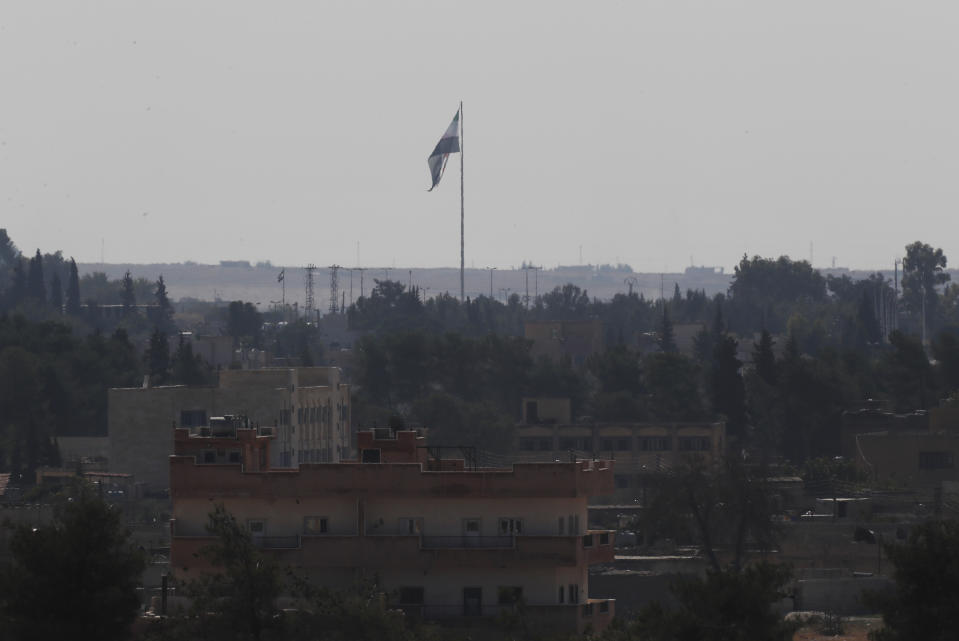 In this photo taken from the Turkish side of the border between Turkey and Syria, in Akcakale, Sanliurfa province, southeastern Turkey, Syria's opposition flag flies on a pole in Tal Abyad, Syria, Wednesday, Oct. 23, 2019. Russian media reports say Russian military police have started patrols in northern Syria as a Turkish-Russian agreement giving Syrian Kurdish fighters 150 hours to withdraw from almost the entire northeast border region of Syria came into effect. (AP Photo/Lefteris Pitarakis)