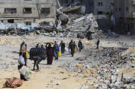 Palestinians walk through the destruction left by the Israeli offensive on Khan Younis, Gaza Strip, Friday, March 8, 2024. (AP Photo/Hatem Ali)