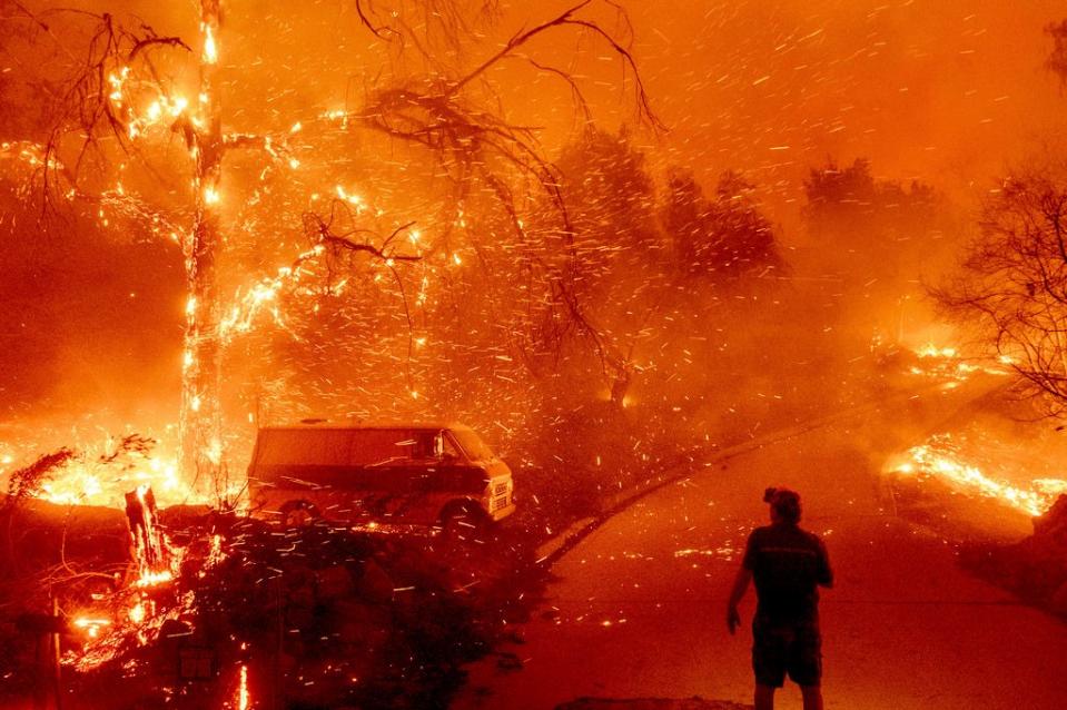 Bruce McDougal watches embers fly over his property as the Bond Fire burns through the Silverado community in Orange County, Calif., on Thursday, Dec. 3, 2020.