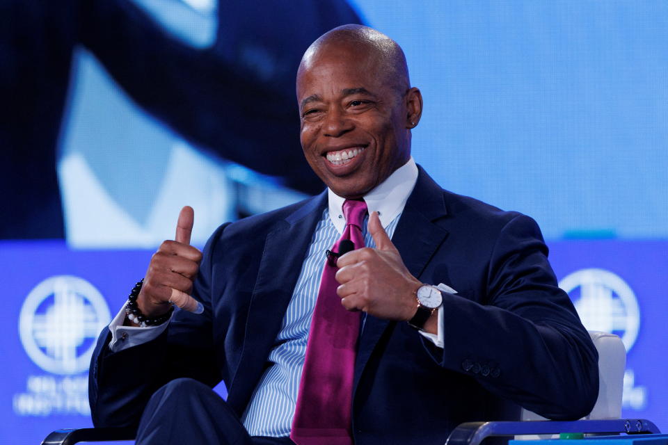 Eric Adams gives a double thumbs-up while seated.