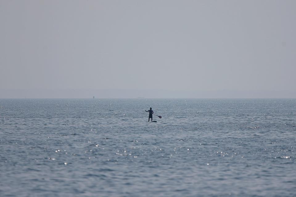 A man paddles his boat in Buzzards Bay on a foggy morning as seen from Fort Taber Park in New Bedford.