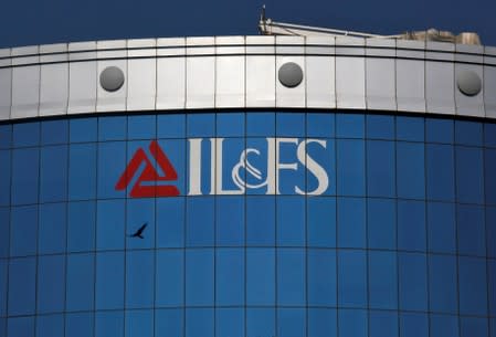 A bird flies next to the logo of IL&FS installed on the facade of a building at its headquarters in Mumbai
