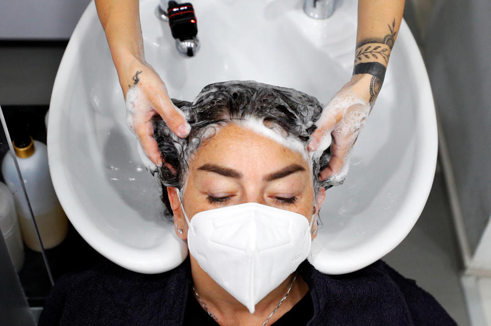 A customer wearing a face mask has her hair washed in a salon in Rome.