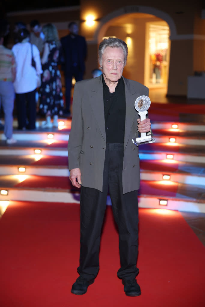 Man in a suit holding an award on the red carpet