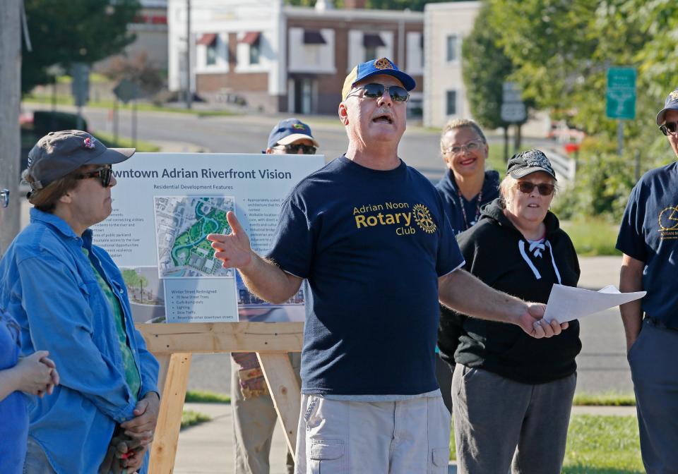 Mark Murray of the Adrian Noon Rotary Club speaks to volunteers at a River Raisin cleanup event Aug. 27, 2022, in downtown Adrian, held with support from the River Raisin Watershed Council. Behind Murray and displayed at this summer's river cleanup were informational charts and renderings of the Downtown Adrian Riverfront Vision Plan.