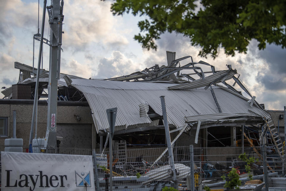 The roof of a construction machinery dealer lies across the building during a storm in Paderborn, Germany, Friday, May 20, 2022. A tornado swept through the western German city of Paderborn on Friday, injuring at least 30 people as it blew away roofs, toppled trees and sent debris flying for miles, authorities said. (Lino Mirgeler/dpa via AP)