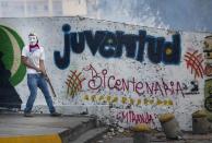 <p>A masked anti-government protester holds a piece of metal in Caracas, Venezuela, on Feb. 22, 2014. After the opposition rally broke up in the late afternoon, in a pattern seen in previous demonstrations, about 1,000 stragglers erected barricades of trash and other debris and threw rocks and bottles at police and National Guardsmen. The troops responded with volleys of tear gas to prevent the students from reaching a highway and blocking traffic. (Photo: Rodrigo Abd/AP) </p>