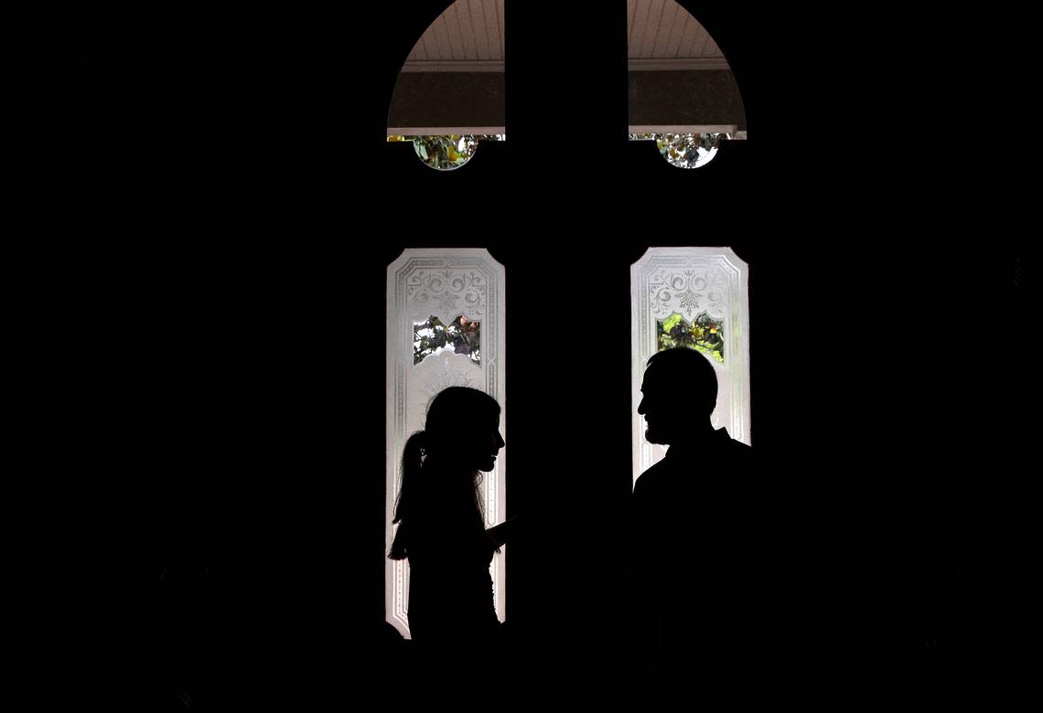 Talia Kuehn is silhouetted by the front door of the Andrews-Duncan House as she talks with Jeff Turpin on May 25, 2023, in Raleigh, N.C. Turpin and his partner, Tina Konidaris, moved with their children into the house in February after spending about five years renovating it. The glass front door is original to the house prior to renovations.