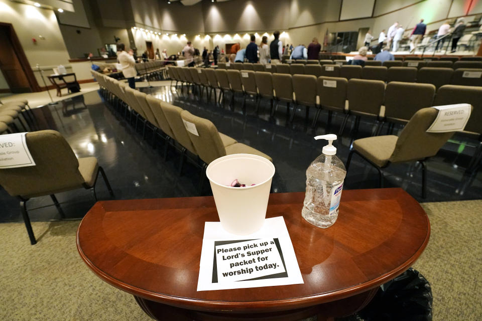 Congregants of Highland Colony Baptist Church are encouraged to spritz their hands with sanitizer before picking up a communion packet, while having a variety of seating options in the Worship Center of Highland Colony Baptist Church, Nov. 29, 2020, in Ridgeland, Miss. The church practices covid protocols by allowing families to sit spaced out from others, separating older and more vulnerable members in the worship hall and providing sanitizer and masks at the entrance. (AP Photo/Rogelio V. Solis)