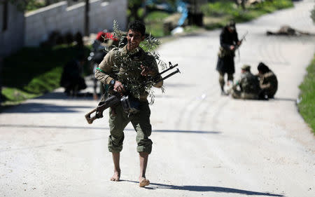 A Turkish-backed Free Syrian Army fighter holds a weapon and olive branches north of Afrin, Syria March 17, 2018. REUTERS/Khalil Ashawi