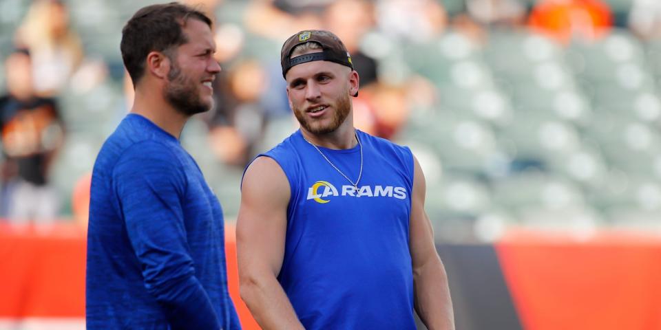 Matthew Stafford and Cooper Kupp stand on the field before a preseason game and talk while wearing plain clothes.