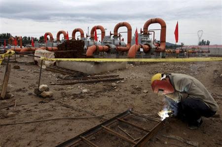 A labourer welds a steel frame next to natural gas pipes at a receiving terminal on the outskirts of Beijing, September 23, 2013. REUTERS/Stringer