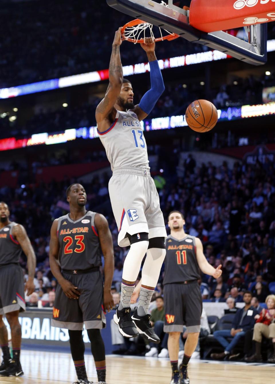 Eastern Conference forward Paul George (13), of the Indiana Pacers, slam dunks in front of Western Conference forward Draymond Green (23), of the Golden State Warriors, and guard Klay Thompson (11), of the Golden State Warriors, during the first half of the NBA All-Star basketball game in New Orleans, Sunday, Feb. 19, 2017. (AP Photo/Gerald Herbert)