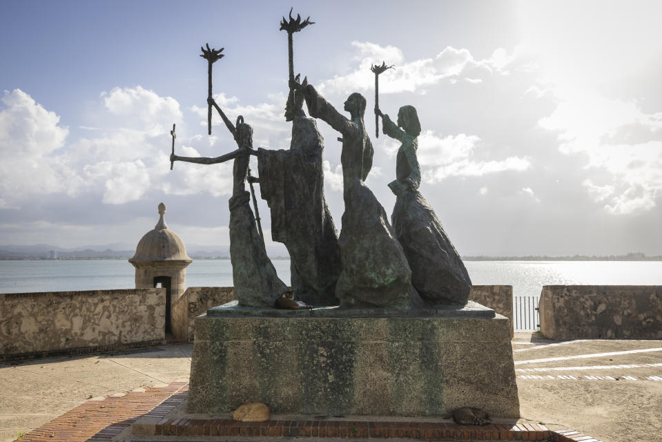 Stray cats rest on a statue in Old San Juan, Puerto Rico, Wednesday, Nov. 2, 2022. Cats have long walked through the cobblestone streets of Puerto Rico's historic district, stopping for the occasional pat on the head as delighted tourists and residents snap pictures and feed them, but officials say their population has grown so much that the U.S. National Park Service is seeking to implement a “free-ranging cat management plan” that considers options including removing the animals. (AP Photo/Alejandro Granadillo)