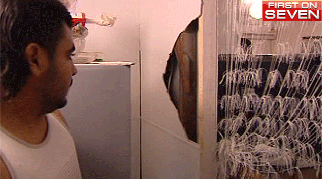 Zena's husband inspects the wall intruders broke down in their hunt for cash, during a terrifying home invasion. Photo: 7News