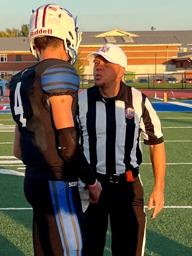 A referee talks with Highland quarterback Kolton Stover before their home football game with River Valley last fall.