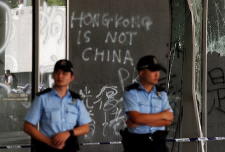 Policemen stand in front of graffiti on the walls of the Legislative Council, a day after protesters broke into the building in Hong Kong