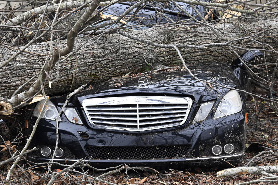 A Mercedes-Benz parked near a home is crushed by a tree, Sunday, Dec. 10, 2023, in Clarksville, Tenn. Tornados caused catastrophic damage in Middle Tennessee on Saturday afternoon and evening, Dec. 9. (AP Photo/Mark Zaleski)
