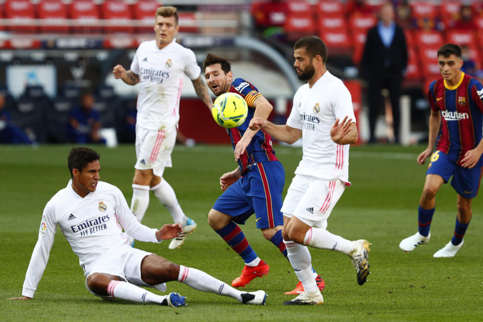 El delantero del Barcelona Lionel Messi (medio) pugna el balón con Raphael Varane y Nacho (derecha) del Real Madrid en el partido de La Liga española, el sábado 4 de octubre de 2020. (AP Foto/Joan Monfort)