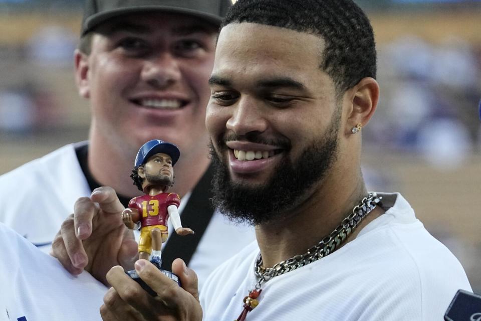 USC quarterback Caleb Williams holds a bobblehead of himself prior to a Dodgers game