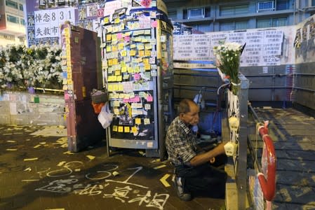 Lou Tit-Man, 73, reacts in front of a Lennon Wall outside Mong Kok police station in Hong Kong