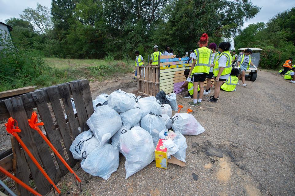 Collected trash from dumping on Percy V. Simpson Drive piles up for removal during a Jackson Citywide Day of Service Monday, Aug. 28, 2023. The trash buildup from dumping on Simpson Drive prevented anyone from using the road. With debris cleared, murals were painted on pallets that had been dumped.