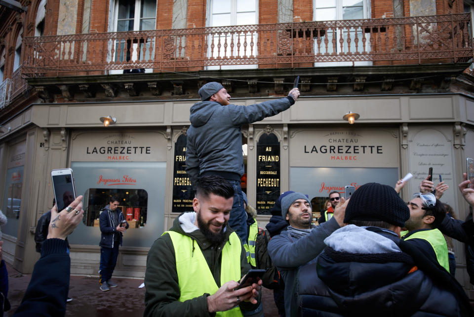 Un manifestante graba con su celular durante las revueltas de los chalecos amarillos en Toulouse, Francia.