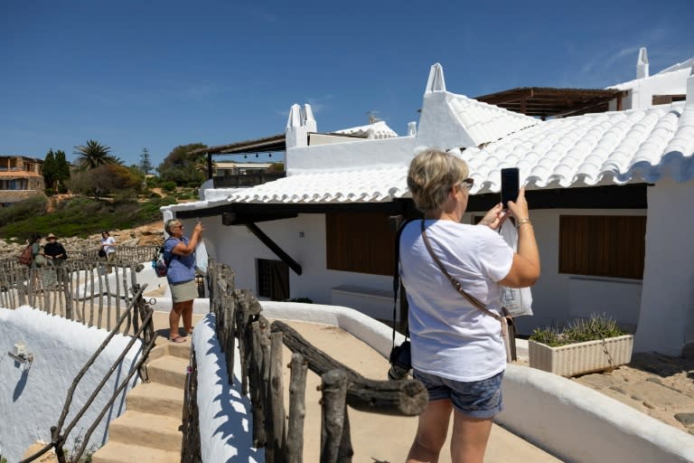 Unos turistas fotografían el pueblo de pescadores de Binibeca, en la localidad española de Sant Lluís, en la isla balear de Menorca, el 30 de mayo de 2024 (Jaime Reina)