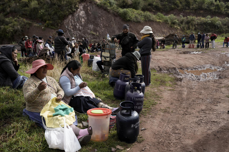 FILE - Quechua women pass the time doing needlework as they wait in a line to buy propane gas for cooking, on the outskirts of Cusco, Peru, Jan. 28, 2023. Roadblocks set up by anti-government protesters seeking the resignation of President Dina Boluarte continue across the countryside, leading to shortages of gas and other staples.(AP Photo/Rodrigo Abd, File)