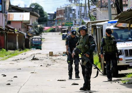 Policemen stand guard along the main road of Marawi City, as government forces continue their assault against insurgents from the Maute group, who have taken over large parts of Marawi City, Philippines June 22, 2017. REUTERS/Romeo Ranoco