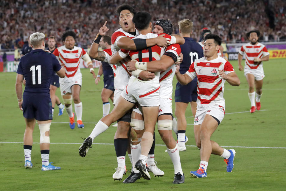 Japan's Kenki Fukuoka is congratulated by his teammates after scoring his team's third try during the Rugby World Cup Pool A game at International Stadium between Japan and Scotland in Yokohama, Japan, Sunday, Oct. 13, 2019. (AP Photo/Christophe Ena)