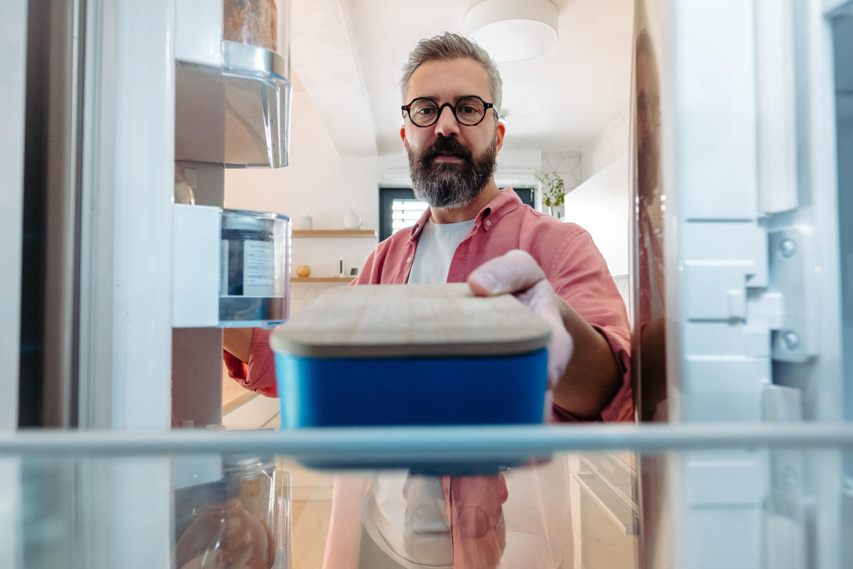 Power out? How to keep your food safe. A man reaches for a container in a refrigerator. 