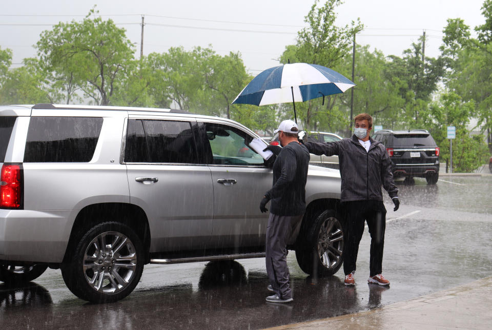 Texas quarterback Sam Ehlinger holds up an umbrella for coach Tom Herman as he hands out school curriculum to a family at an Austin-area Boys & Girls club. (Photos courtesy Boys & Girls Club of the Austin Area)