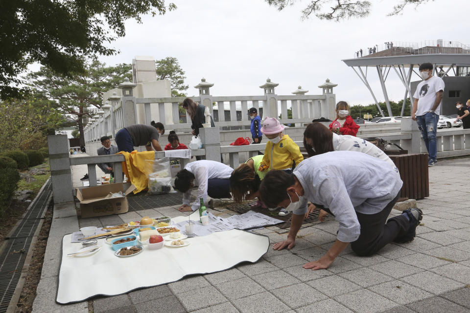 North Korean defector Yoo Soon-nyeo, fifth from right, and her family members bow to respect their ancestors in North Korea to celebrate the Chuseok, the Korean version of Thanksgiving Day, at Imjingak Pavilion in Paju, near the border with North Korea, South Korea, Thursday, Oct. 1, 2020. The government has discouraged people from visiting their hometowns for the Chuseok holiday amid concerns about the spread of the coronavirus. (AP Photo/Ahn Young-joon)