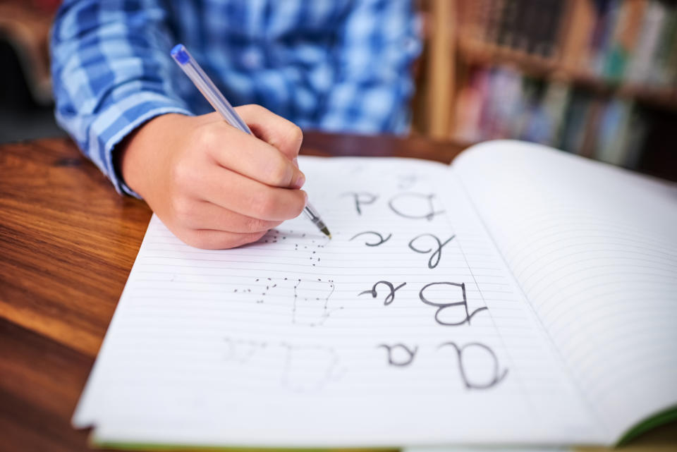 Person practicing writing alphabet on lined paper