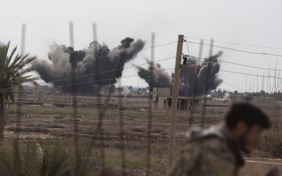 A Syrian Democratic Forces fighter ducks as a pair of coalition airstrikes hit territory controlled by Isil near the town of Baghuz - Sam Tarling