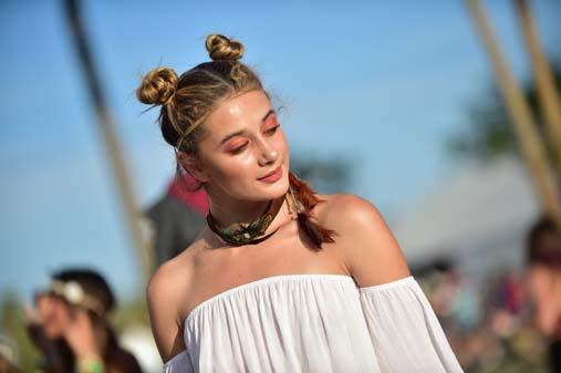 Festivalgoer sports double topknots and bright orange eyeshadow during Day 3 of Coachella.