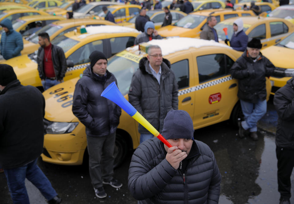 FILE - In this Wednesday, Feb. 13, 2019, file photo a taxi driver blows into a horn during a protest against ride hailing services in Bucharest, Romania. The Romanian government has issued an emergency decree ramping up steep fines for drivers of ride-hailing services like Uber and Taxify. The decree taking effect Thursday, May 16, 2019 fines drivers transporting people in their car without a valid taxi license up to $1,175 (1,050 euros) already from the first offense. Previously, drivers were fined only after repeated offenses. (AP Photo/Vadim Ghirda, File)