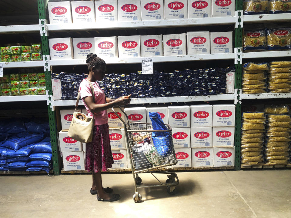 A woman does a quick calculation on her phone before buying groceries at a shop in Harare, in this Wednesday, Oct, 9, 2019 photo. Hyperinflation is changing prices so quickly in the southern African nation that what you would see displayed on a supermarket shelf might change by the time you reach the checkout. (AP Photo/Tsvangirayi Mukwazhi)