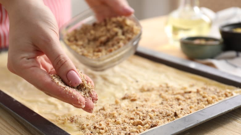 Person spreading nuts onto baklava