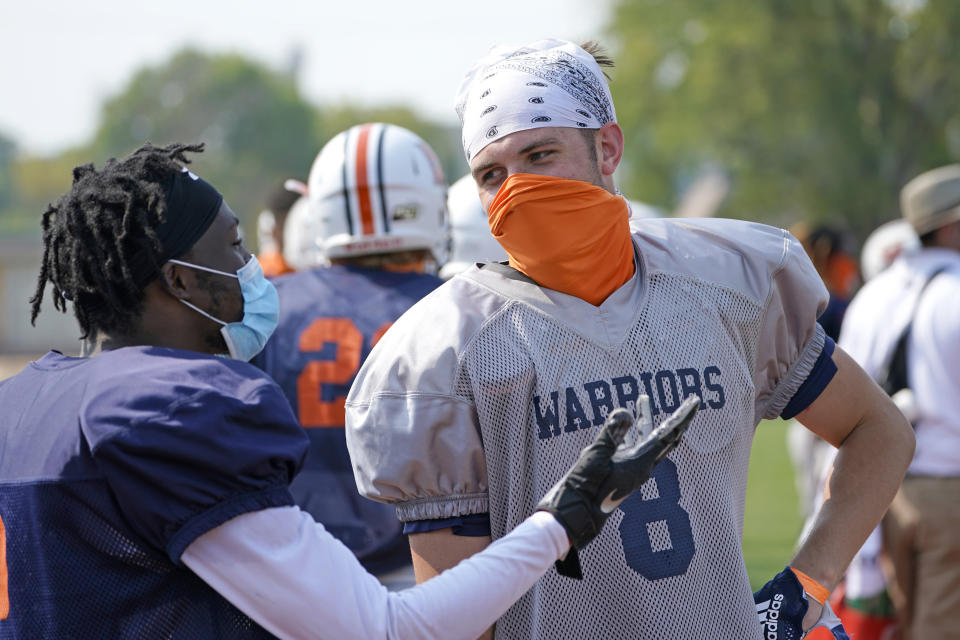 Midland University tight end Austin Harris, right, chats with a teammate during NAIA college football team practice in Fremont, Neb., Tuesday, Aug. 25, 2020. Midland University is among five small colleges in the state that are pushing forward with plans to play football this fall. The Nebraska Cornhuskers, meanwhile, won't play after Big Ten presidents voted to move back football season until after Jan. 1. (AP Photo/Nati Harnik)