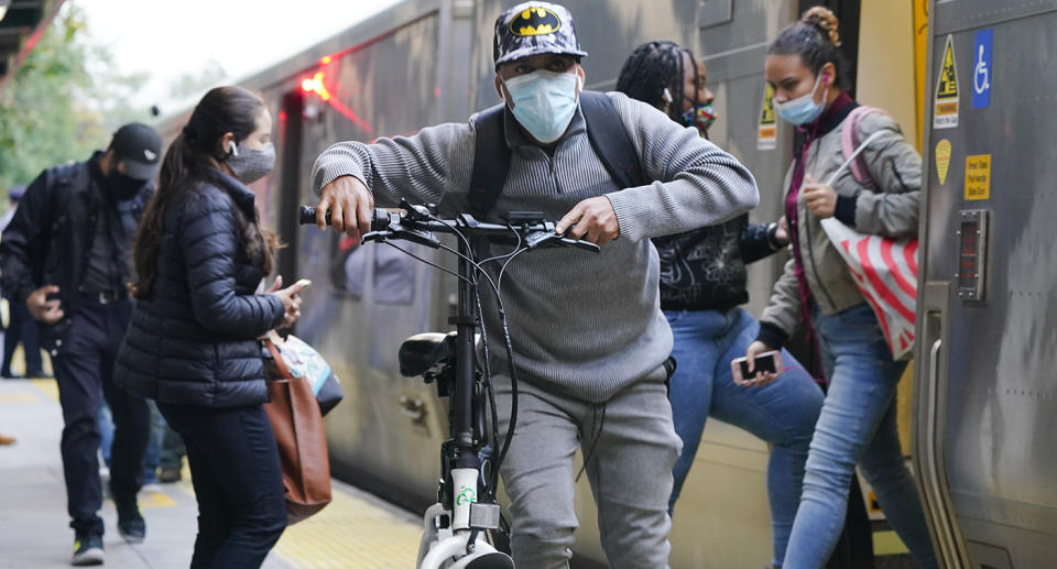 People exit and board a train wearing masks in the US.