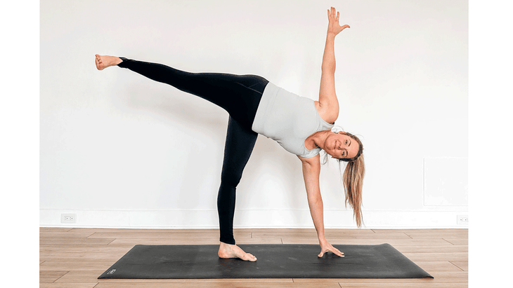 Yoga teacher builds core strength practicing Half Moon Pose on a yoga mat