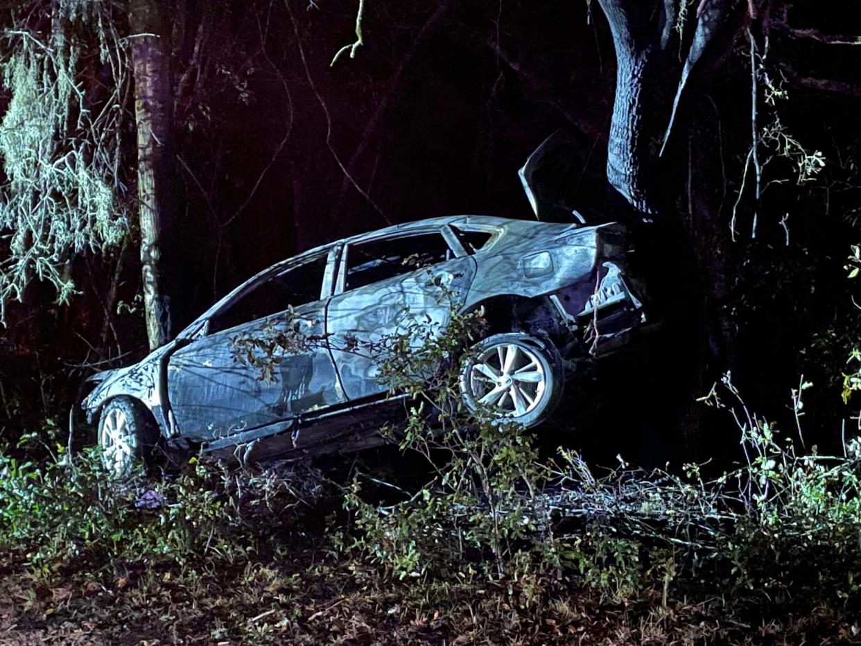 FHP troopers investigate how a car ended up between two trees along County Road 464C late Tuesday night.