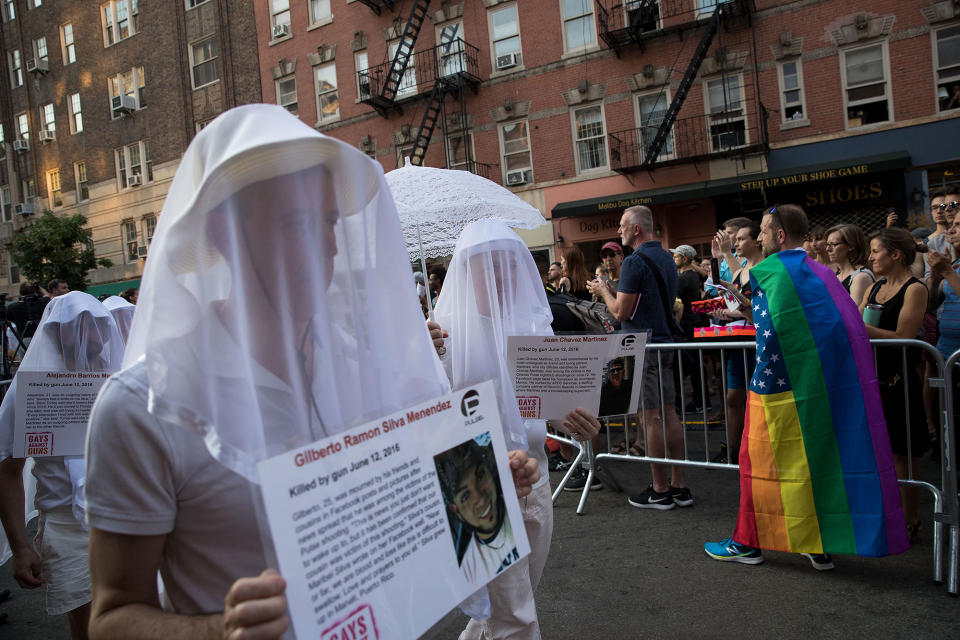 <p>People dressed in white hold photos of victims from the 2016 Pulse nightclub shooting during a memorial service and rally down the street from the historic Stonewall Inn, June 12, 2017 in New York City. (Photo: Drew Angerer/Getty Images) </p>