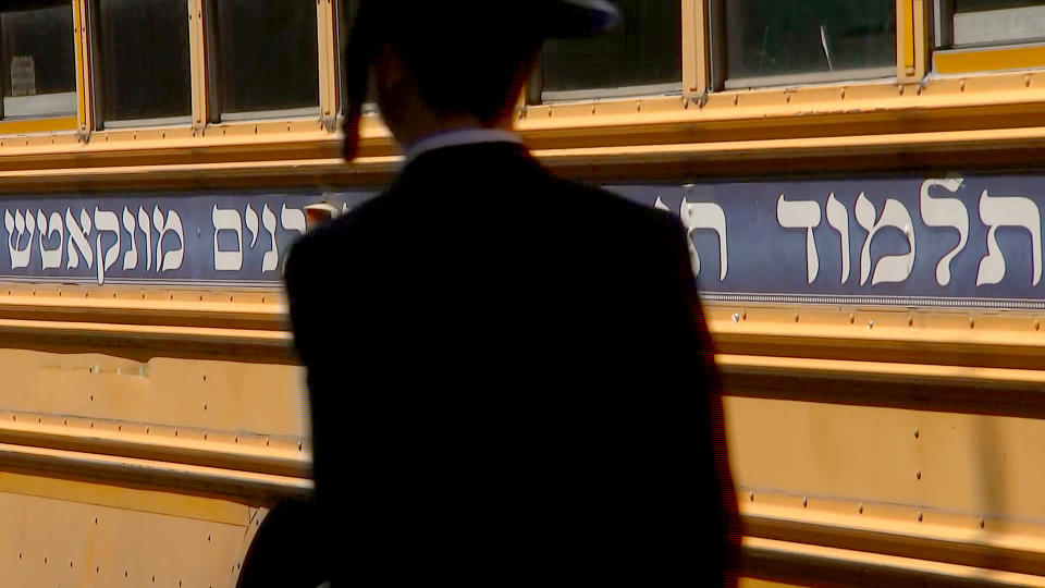 An Orthodox Jewish man walks in front of a school bus in the predominantly Hasidic neighborhood of Borough Park in Brooklyn, N.Y. (NBC News)