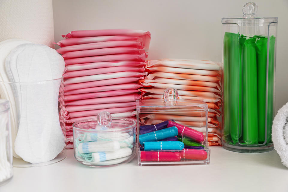 assortment of period pads and tampons on a bathroom shelf